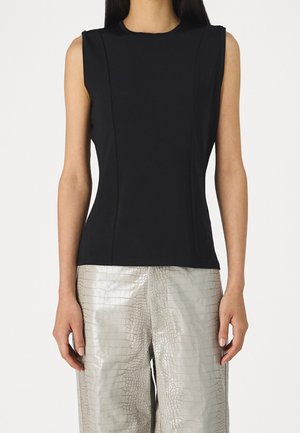 Sleeveless black fitted top paired with light gray wide-leg pants featuring a shiny crocodile texture pattern.