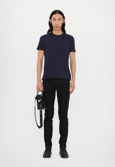 Camiseta de manga corta navy, jeans negros rectos, bolso negro con correa y zapatos negros. Textura suave, detalle de bolsillo en la camiseta.