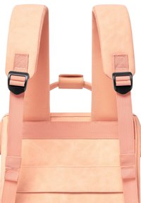 Peach-colored backpack featuring padded, adjustable straps, a rectangular structure, and a textured finish. Includes a top handle for grip.