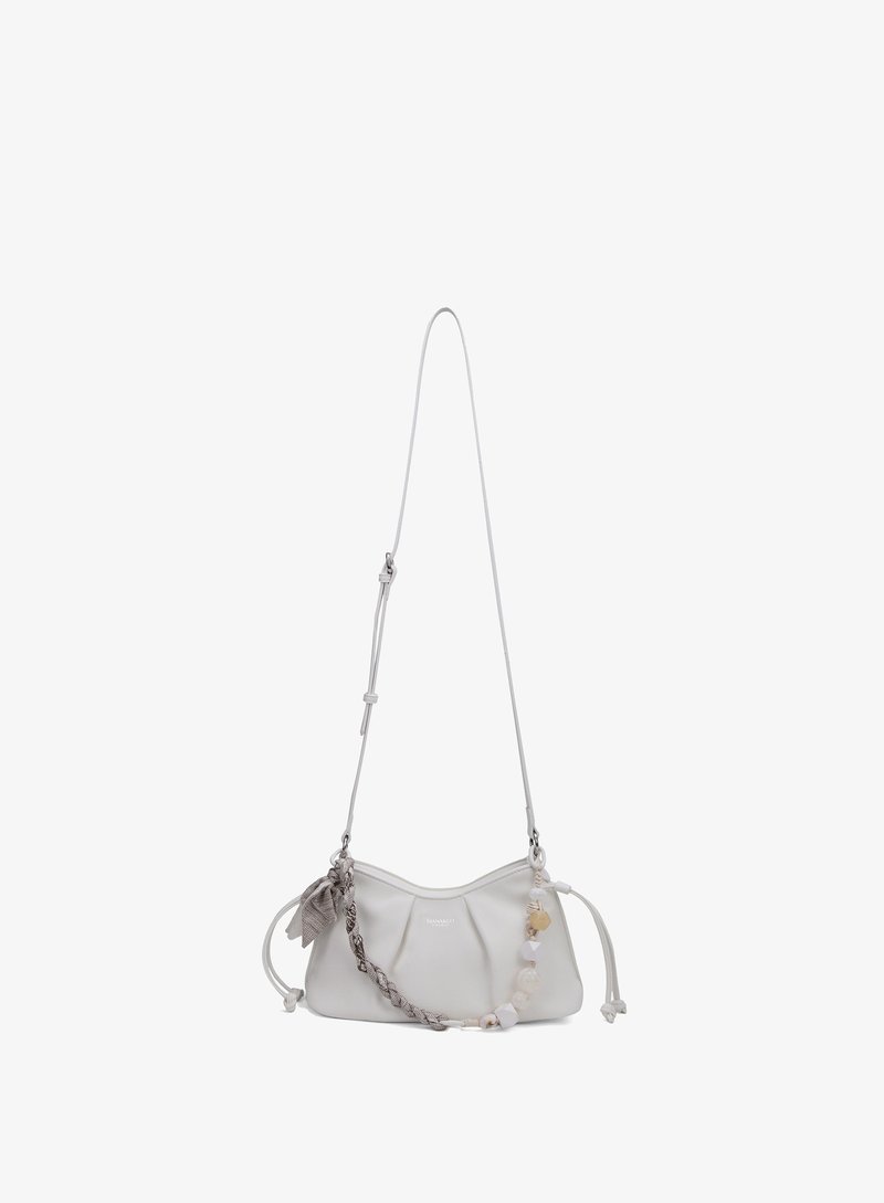 Petit sac d'épaule blanc avec une sangle réglable, un détail tressé et des perles décoratives sur un fond uni.