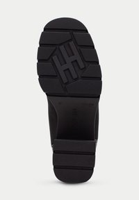 Suela de zapato de goma negra con surcos profundos para tracción, con un logotipo en relieve y marcado de tamaño, bordes lisos y construcción resistente.