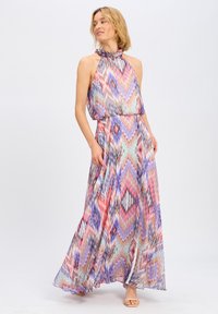 Maxi dress in tessuto leggero con un motivo zigzag colorato. Design a colletto halter con una vestibilità ampia e un orlo fluido. Toni di viola, rosa e verde.
