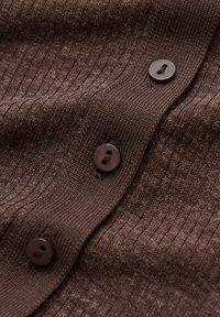 Brown ribbed cardigan featuring four dark brown buttons, soft texture, and a close-knit design, emphasizing the fabric's thickness and pattern.