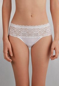 Witte slip met een kanten tailleband met bloemenpatroon, van gladde stof en een klassieke snit, die een zachte textuur en verfijnde details biedt.