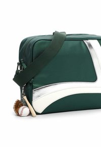 Grøn nylon crossbody taske med sølv- og hvide accenter, der har en aftagelig nøglering med baseballhandske, bold og bat.