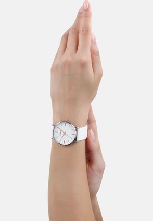 White watch with a round face, silver metal casing, and rose gold hour markers. Features a smooth white silicone strap.