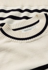 Strickpullover in creme mit schwarzen wellenförmigen Streifen. Verfügt über einen gerippten Kragen und Bündchen, mit dem Markenetikett sichtbar in der Nähe des Ausschnitts.