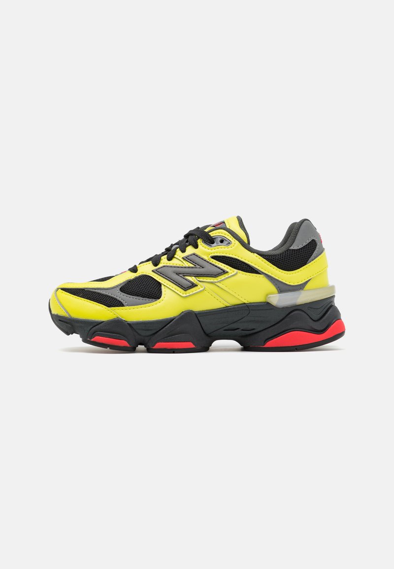 Yellow and black athletic shoe with mesh and synthetic material, rounded toe, prominent cushioning, gray accents, and red sole details.