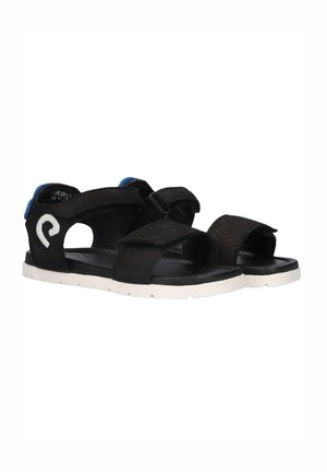 Sandales noires en tissu avec des straps en Velcro, dotées d'une semelle blanche, d'accents bleus au talon et d'une semelle intérieure texturée.