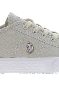 Light grey fabric sneaker with white laces, a small polo player logo on the side, and "POLO ASSN." embossed on the white sole.