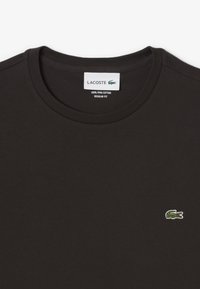 Sort bomulds T-shirt med ribbet rund halsudskæring og et lille broderet grønt krokodillelogo på venstre bryst. Regular fit design.