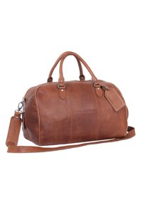 Borsa da viaggio in pelle marrone con forma curva, manici superiori, tracolla regolabile, chiusura con zip e dettagli con etichetta per bagagli.
