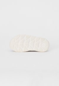 Leichter Sneaker-Sohle aus weißem Gummimaterial, mit strukturiertem Muster und multidirektionalem Profil für bessere Traktion.