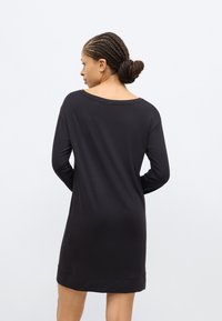 Black long-sleeve dress with a relaxed, wide neckline, smooth texture, and above-knee length. Minimalist design, no visible patterns or accents.