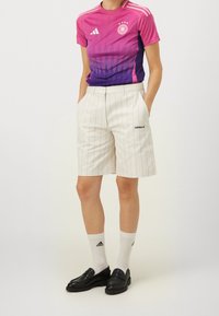 Różowo-fioletowy gradientowy t-shirt Adidas z logo; białe spodenki w paski; czarne loafersy; białe skarpetki z logo; swobodny styl sportowy.