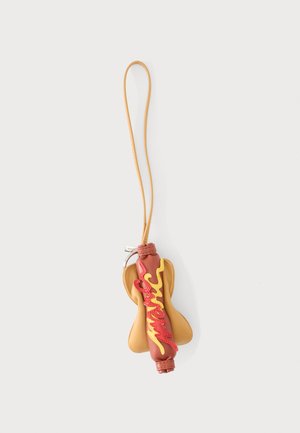 Schlüsselanhänger in Form eines Hotdogs mit brauner Wurst, gelben und roten Wellenlinien, die Senf und Ketchup darstellen, und einem hellbraunen Brötchen mit Lederriemen.