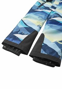 Niebieskie i czarne spodnie narciarskie z wzorem górskim, wzmocniony czarny materiał na wewnętrznych mankietach oraz elastyczne ochraniacze śnieżne z zatrzaskami.