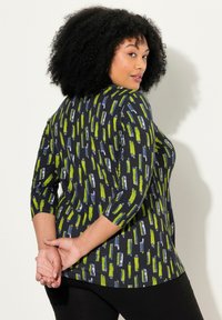 Flerfärgad topp med en marinblå bas och abstrakta mönster i grönt och grått, rund hals, ¾ ärmar och en avslappnad passform.