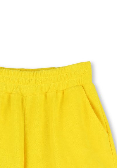 Pantaloni da tuta gialli con un elastico in vita, realizzati in un tessuto morbido e testurizzato e dotati di tasche laterali.