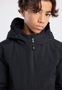 Black hooded jacket with a front zipper, smooth texture, and elasticized cuffs. Features a high collar and minimalistic design.