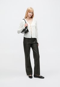 Lightweight white blouse with tie-front closure and lace detailing, paired with high-waisted dark leather pants and black flat shoes.