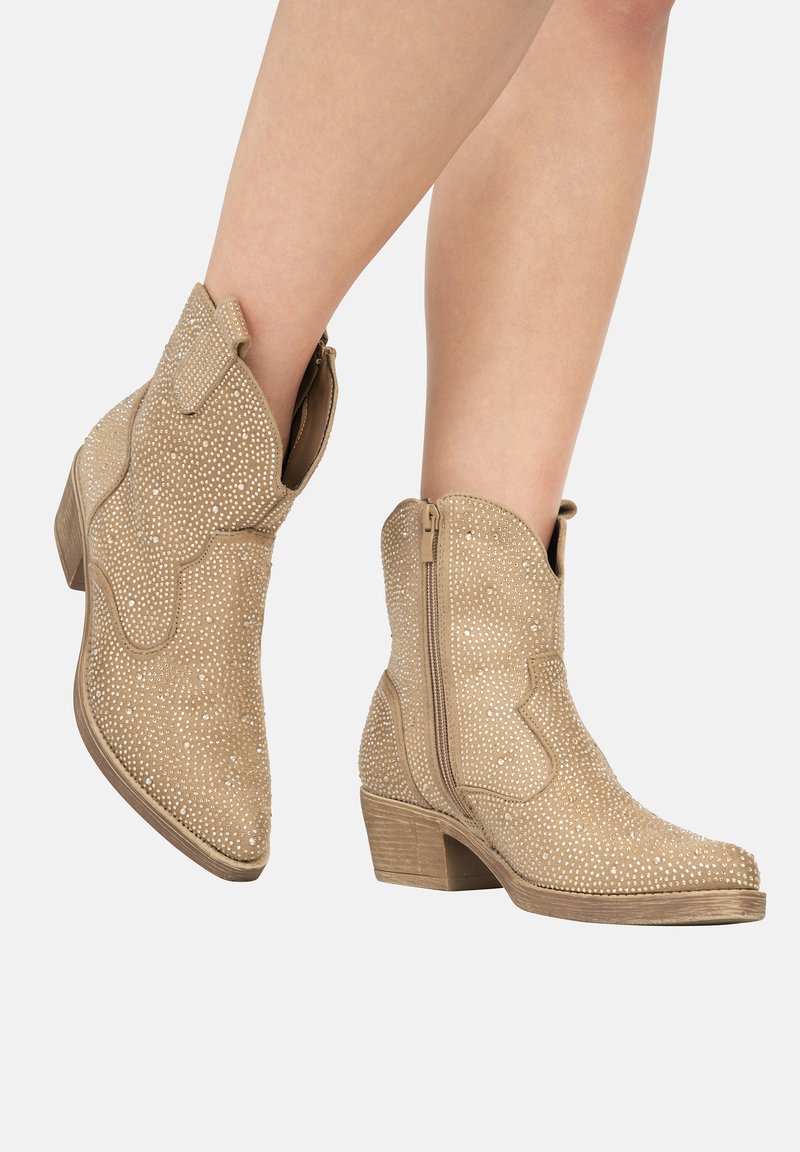 Botas de cowboy beige con ante texturizado, adornadas con pequeñas tachuelas, con una cremallera lateral y un tacón apilado.