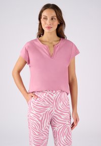 Top rosa de manga corta con escote en V y borde de encaje, combinado con pantalones de patrón de cebra rosa y blanco. Tejido suave con un ajuste relajado.
