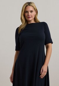 Σκούρο ναυτικό φόρεμα από μαλακό, ελαστικό ύφασμα. Διαθέτει στρογγυλή λαιμόκοψη, κοντά μανίκια και φαρδιά σχεδίαση που κρέμεται από τη μέση.