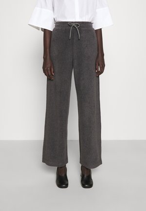 Ciemnoszare dzianinowe szerokie spodnie z elastycznym pasem i sznurkiem, noszone z czarnymi butami na obcasie i białą bluzką.