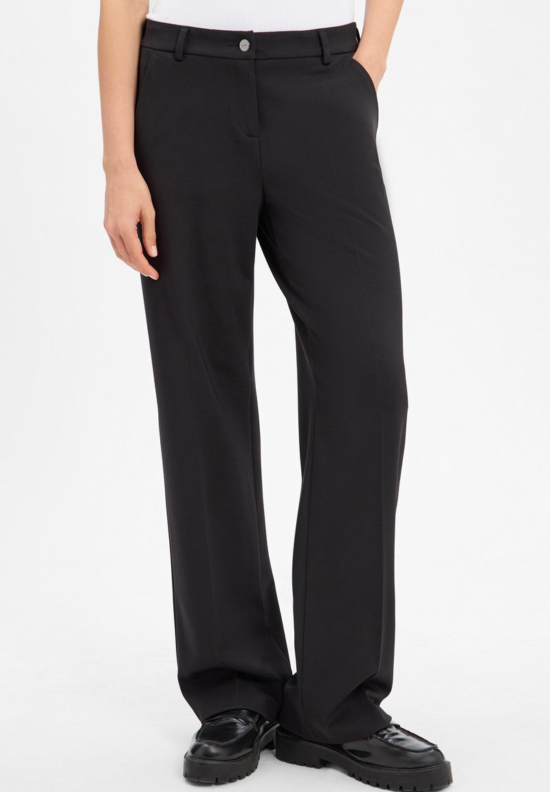 Black tailored trousers with a loose fit, featuring a smooth fabric, straight legs, a front button closure, and side pockets.