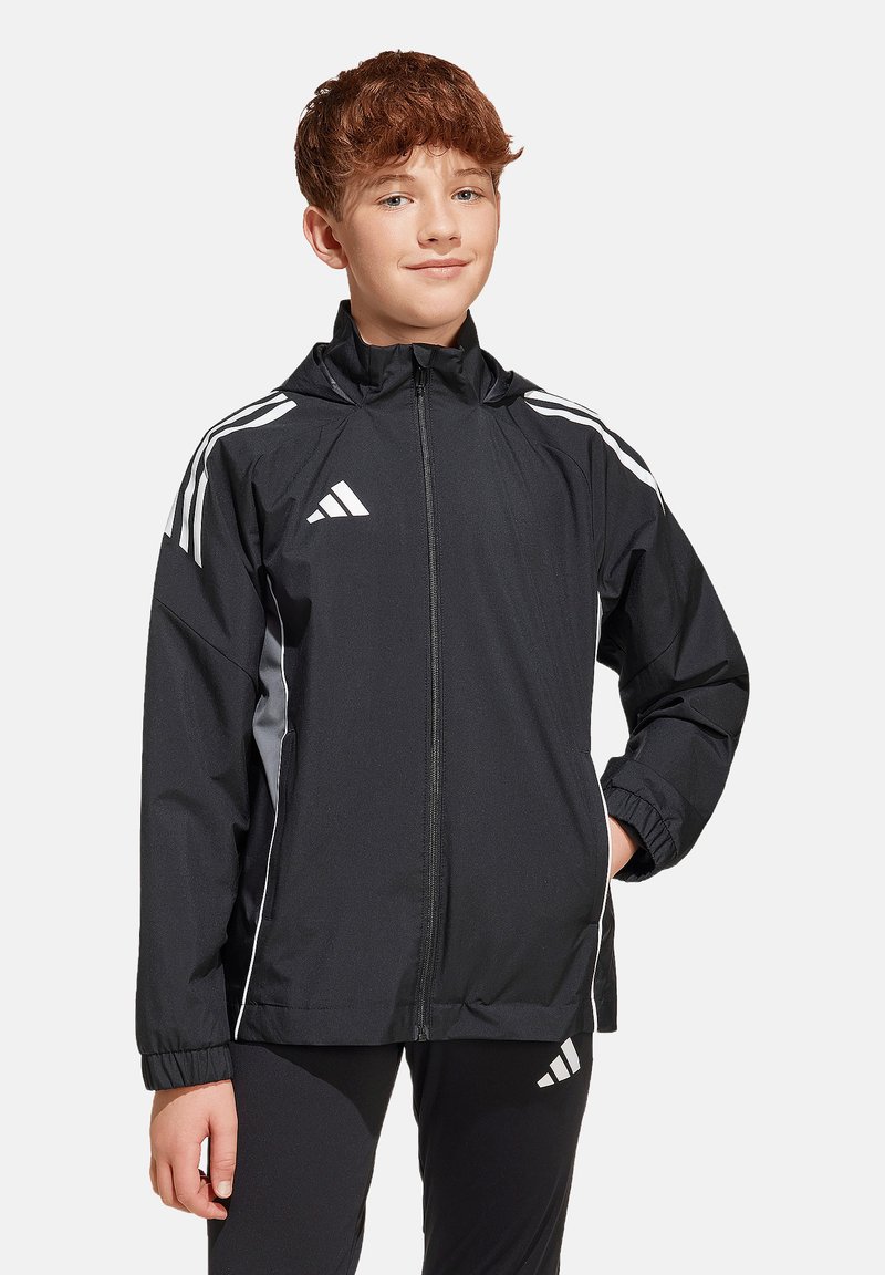 Zwarte Adidas-jack met witte strepen, ritssluiting aan de voorkant, verstelbare capuchon, elastische manchetten en zijzakken. Lichtgewicht, sportief ontwerp geschikt voor gebruik buitenshuis.