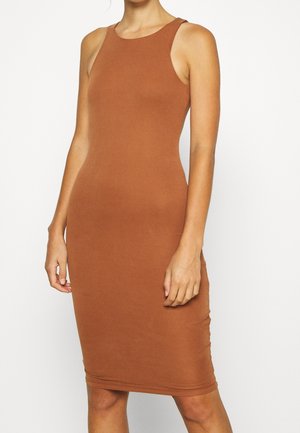 Dopasowana sukienka midi bez rękawów w jednolitym rdzawego brązu, noszona przez osobę stojącą na tle jednolitego białego tła.