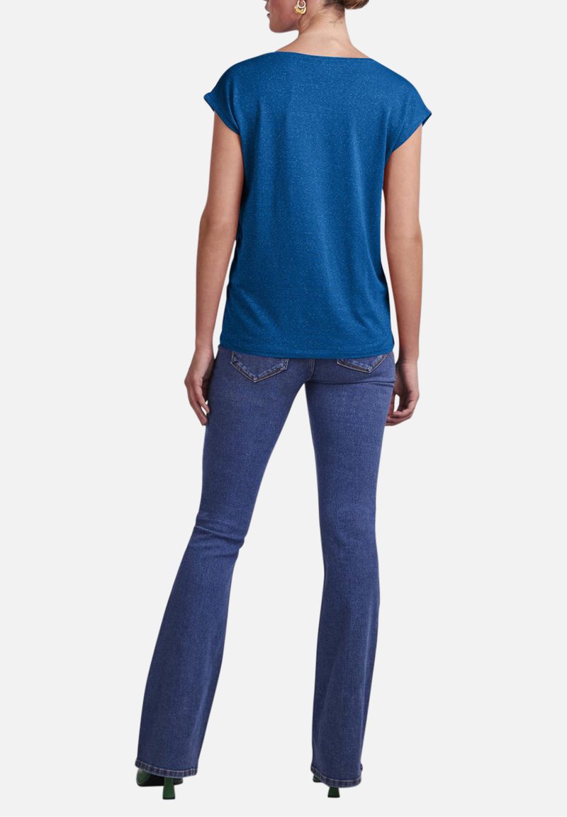 Top azul de manga corta en un tejido texturizado, combinado con jeans acampanados azul oscuro. Presenta un escote redondo y un corte relajado.