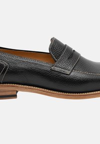 Mocassino in pelle nera con finitura testurizzata, dettagli cuciti e suola in legno marrone chiaro. Presenta una striscia decorativa sopra il collo del piede.