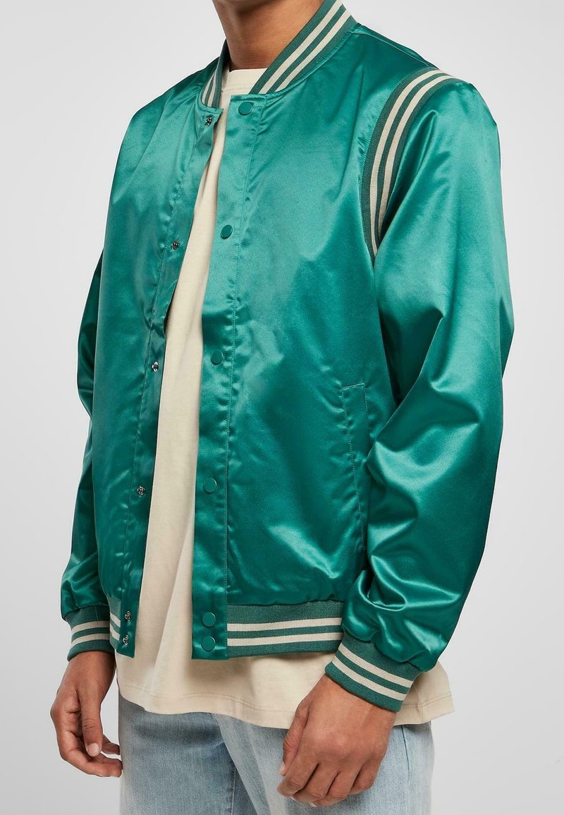 Grüne Satin-Bomberjacke mit Druckknopfverschluss, gestreiftem geripptem Kragen und Bündchen. Glatte Textur mit Seitentaschen.