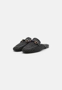 Black woven slip-on shoes with a flat sole, featuring a decorative gold chain and textured surface. No visible patterns or accents.
