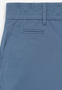 Světle modré bavlněné šortky s elastickým pasem, které mají jednu zadní kapsu a hladkou texturu.