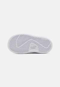 Suola di sneaker bianca con un motivo a zigzag e il logo Puma. Presenta un materiale in gomma liscio e non marcante con variazioni di texture.