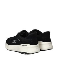 Zwarte sport schoenen met een gestructureerde bovenkant, opvallend logo, comfortabele witte zool en "ARCHFIT" branding aan de zijkant. Details van de rubberen buitenzool zichtbaar.