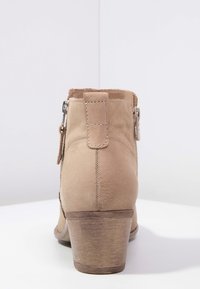 Tan suede nilkkurit, joissa on lyhyt pinoeltu korko. Varusteena on sivuvetoketju ja teksturoitu takapaneeli. Hieno viimeistely, jossa on minimaalinen ompelutieto.