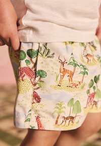 Kleurrijke katoenen shorts met dieren- en plantenpatronen in tinten geel, groen en rood, met een zachte, textuurrijke afwerking.