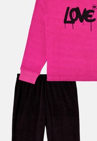 Fleece loungewear sæt bestående af en lys pink langærmet top med sort "LOVE" print og sorte bløde bukser med elastisk talje.