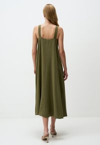 Abito senza maniche verde oliva con una silhouette fluida, caratterizzato da spalline larghe e lunghezza fino al polpaccio, realizzato in un morbido tessuto testurizzato.