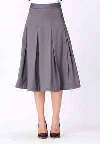 Jupe plissée grise avec une taille ajustée, longueur genoux, fabriquée en tissu léger, associée à des escarpins noirs.