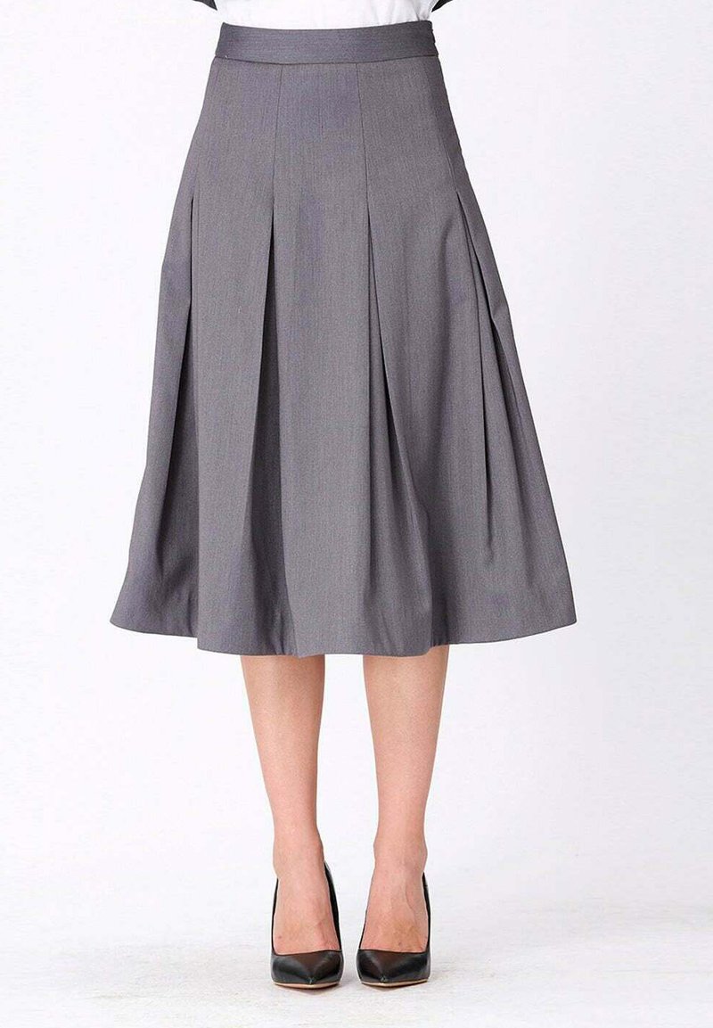 Jupe plissée grise avec une taille ajustée, longueur genoux, fabriquée en tissu léger, associée à des escarpins noirs.