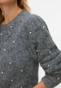 Šedý pletený svetr s texturovanou tkaninou zdobený rozptýlenými perličkami a kulatým výstřihem. Dlouhé, mírně nadýchané rukávy.