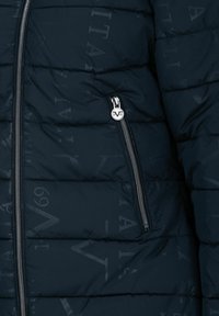 Doudoune marine avec des coutures horizontales, dotée d'une poche zippée et d'un motif logo subtil. Fabriquée en tissu lisse et rembourré.