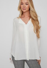 Weiße Chiffonbluse mit V-Ausschnitt, langen Ärmeln und einer Knopfleiste vorne. Glatte Textur mit einem leicht durchsichtigen Erscheinungsbild.