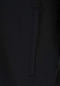 Nahaufnahme eines schwarzen Stoffpaneels mit einer vertikalen Paspeltasche, die saubere Nähte zeigt.