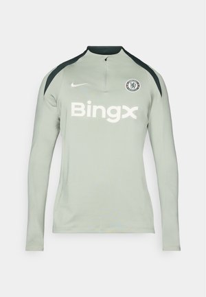 Langärmliges, hellgraues Sportshirt mit schwarzen Schulterakzenten, Reißverschlusskragen, Nike-Logo und dem Text 'Bingx' auf der Vorderseite. Chelsea FC-Logo ist vorhanden.